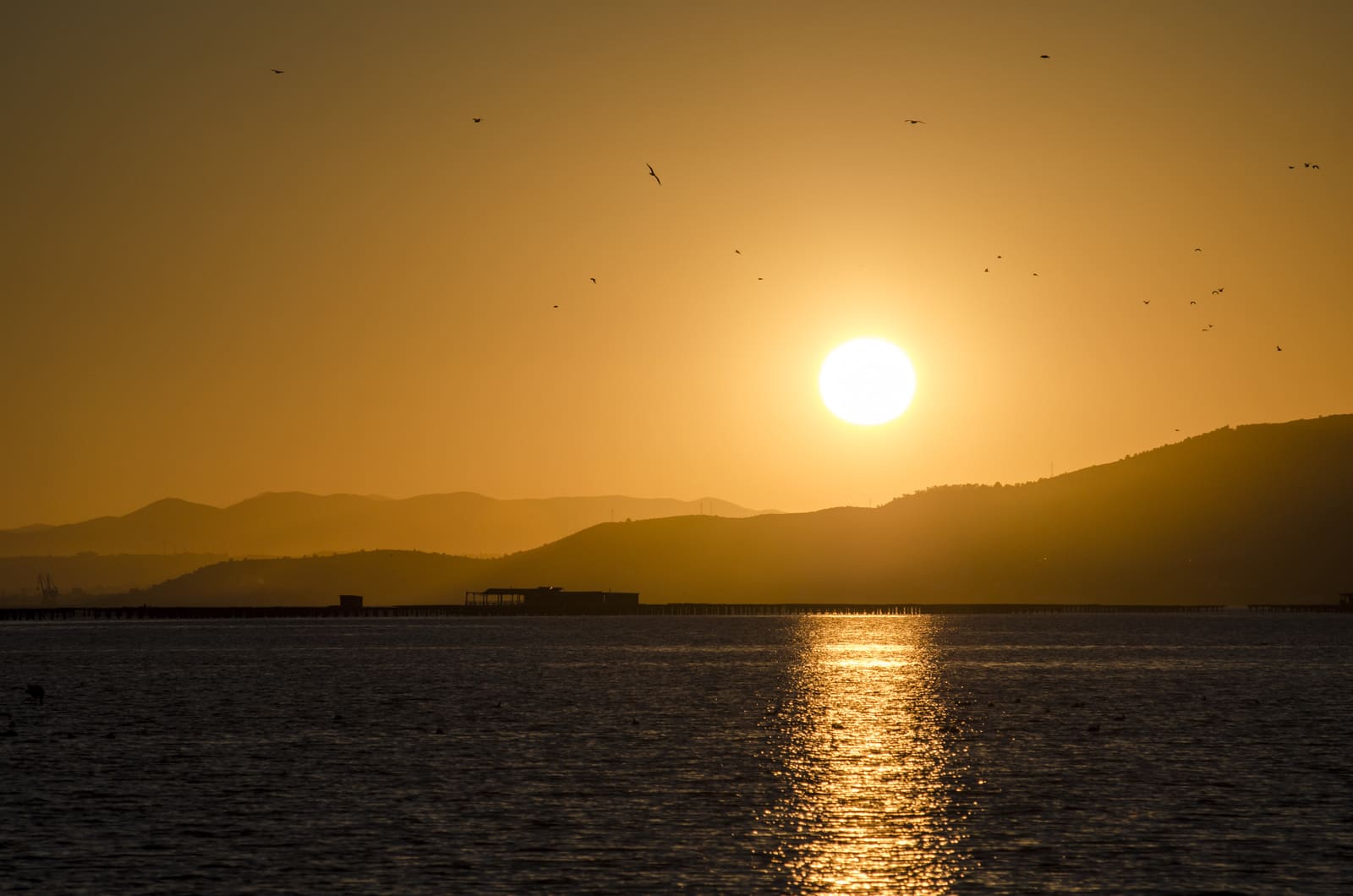 Sol ponent sobre l’aigua amb la serra del Montsià al fons